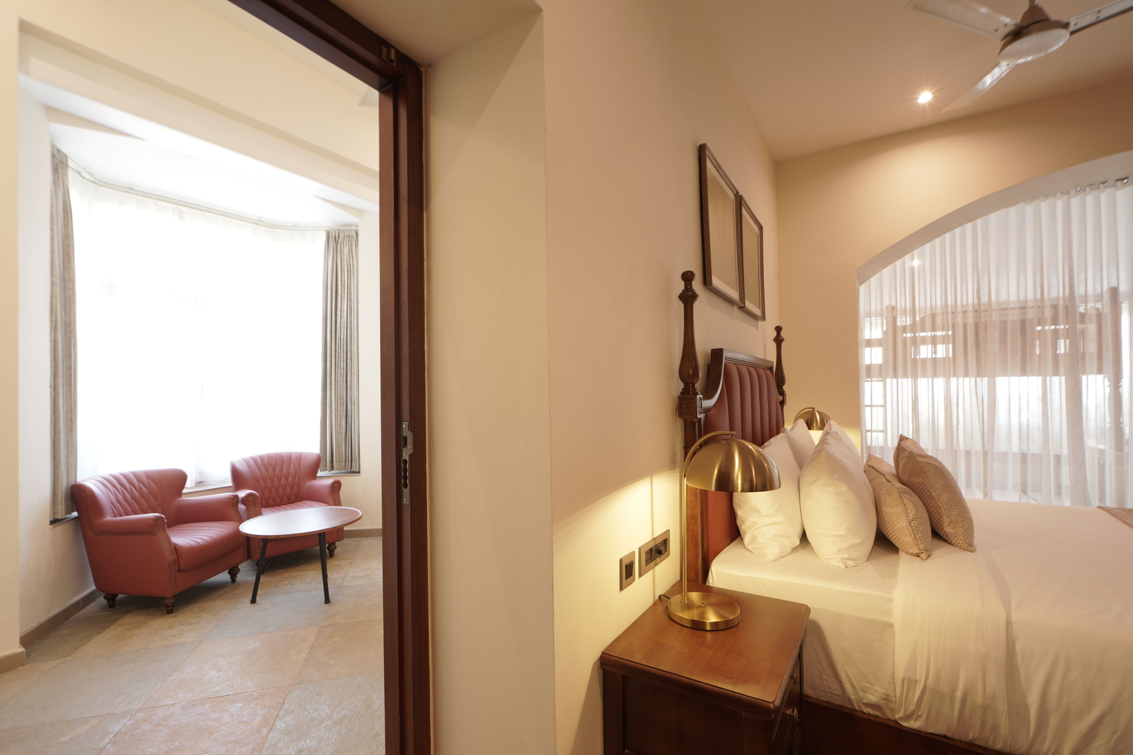 A hotel room with a bed, a bedside table, a lamp, a chair, and a small table.