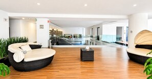 A modern lobby with wicker furniture, a staircase, and a glass railing. - Condesa Loft w/ Balcony, Fast WiFi & Jacuzzi (Mexico City)