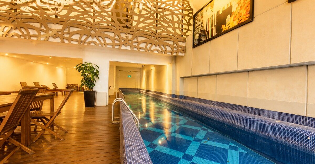 A pool area with a checkered floor, lounge chairs, and a decorative ceiling.