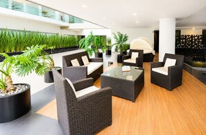 Eine moderne Lounge mit Korbmöbeln, Topfpflanzen und einem Glastisch.