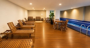 A wooden deck with lounge chairs and tables, a small pool with blue tiles, and a potted plant. - Condesa Loft w/ Balcony, Fast WiFi & Jacuzzi (Mexico City)