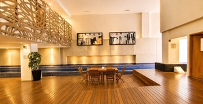 Eine geräumige Lobby mit Holzboden, einer Sitzecke mit Tisch und Stühlen sowie zwei gerahmten Kunstwerken an der Wand.