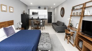 Ein modernes Hotelzimmer mit Bett, einer Sitzecke, einem Essbereich und einem Fernseher.