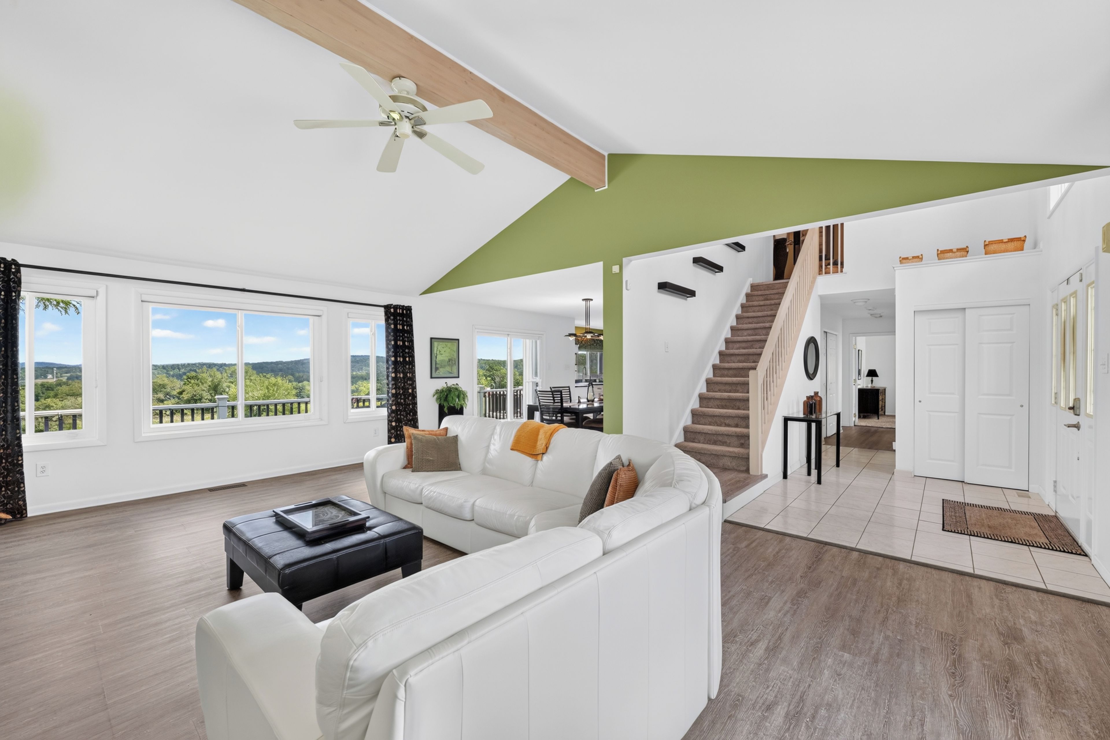A spacious living room with a white sofa, a coffee table, and a view of the outdoors through large windows.