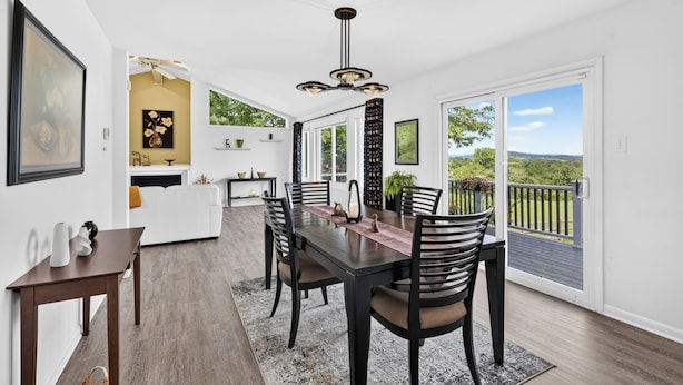 A spacious dining area with a view of the outdoors, a kitchen with a yellow accent wall, and a large window.