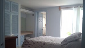 Quarto com cama, guarda-roupa, espelho e janela.