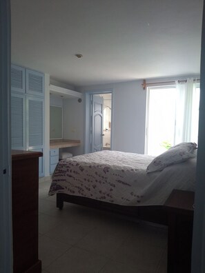 Ein Schlafzimmer mit Bett, Kleiderschrank, Spiegel und Fenster.