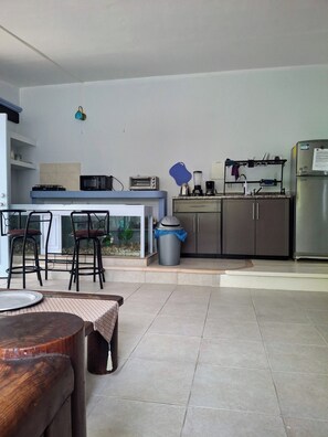 A modern kitchen with a built-in stove, microwave, and toaster. There are bar stools and a trash can. - PURPLE LOTUS COZUMEL (Cozumel)