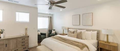 A bedroom with a bed, bedside tables, a ceiling fan, and a window.