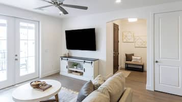 Un salon équipé d’un téléviseur à écran plat, d’un canapé, d’une table basse et d’un ventilateur de plafond.