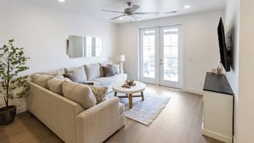 A living room with a sofa, a coffee table, a plant, and a television.