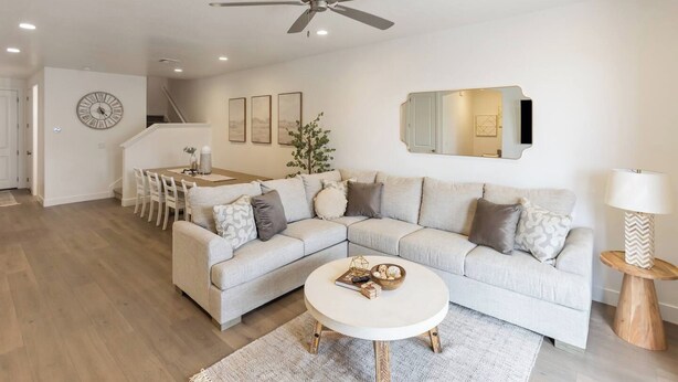 Een moderne woonkamer met een hoekbank, een ronde salontafel en een eethoek met een houten tafel en stoelen.