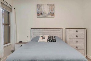 Ein Schlafzimmer mit einem Bett, einem Nachttisch, einer Kommode und einem Bild an der Wand.