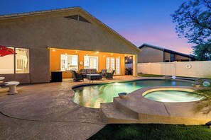 Ein Garten mit Schwimmbad, Sitzgelegenheit im Freien und einer überdachten Terrasse.