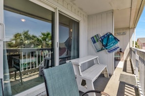 Ein Balkon mit einem Stuhl, einem Tisch und zwei zusammengeklappten Stühlen.