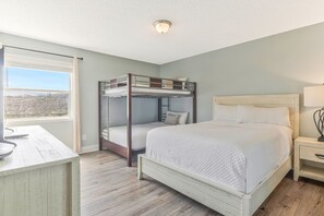 Ein Schlafzimmer mit Etagenbett, Einzelbett, Schreibtisch und Nachttisch.
