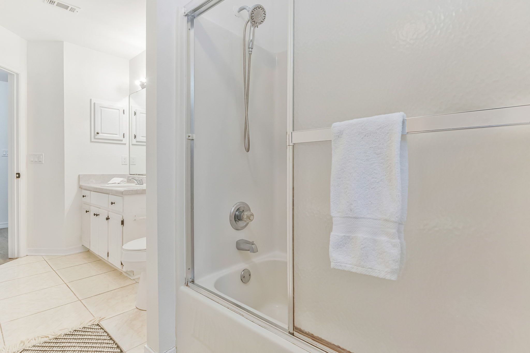 A modern bathroom with a glass-enclosed shower, a white sink, and a towel hanging on the wall.