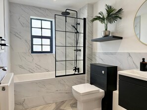 Un bany modern amb plat de dutxa, vàter, rentamig i una planta en test.