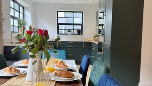 A dining area with a table set for breakfast, including croissants and orange juice. - Chepstow 4BR Retreat | Gated, Garden & Parking (Chepstow)