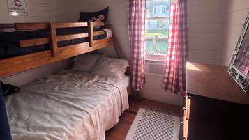 Une chambre avec un lit superposé, une fenêtre avec des rideaux, un radiateur et un panneau indiquant un espace de stationnement.