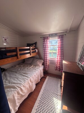 Un dormitorio con literas, una ventana con cortinas, un radiador y un letrero que indica un estacionamiento.