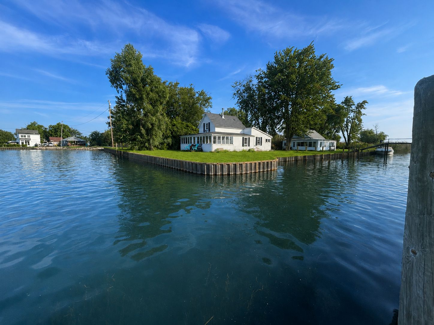 Une maison construite sur un quai, avec une pelouse et un bateau visible au loin.