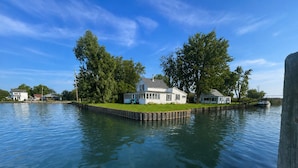 Ein Haus an einer Anlegestelle mit einer Rasenfläche und einem Boot im Hintergrund.