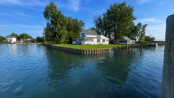 Une maison construite sur un quai, avec une pelouse et un bateau visible au loin.