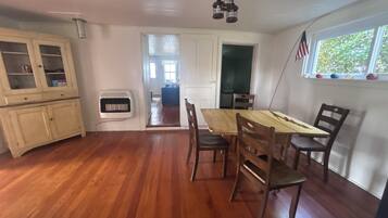 Un coin repas avec une table et des chaises en bois, une fenêtre ornée d’un drapeau américain et une vue sur l’extérieur.