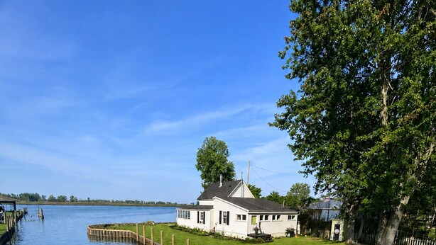 Ein Haus an einem ruhigen See mit einem hölzernen Steg, der sich ins Wasser erstreckt.