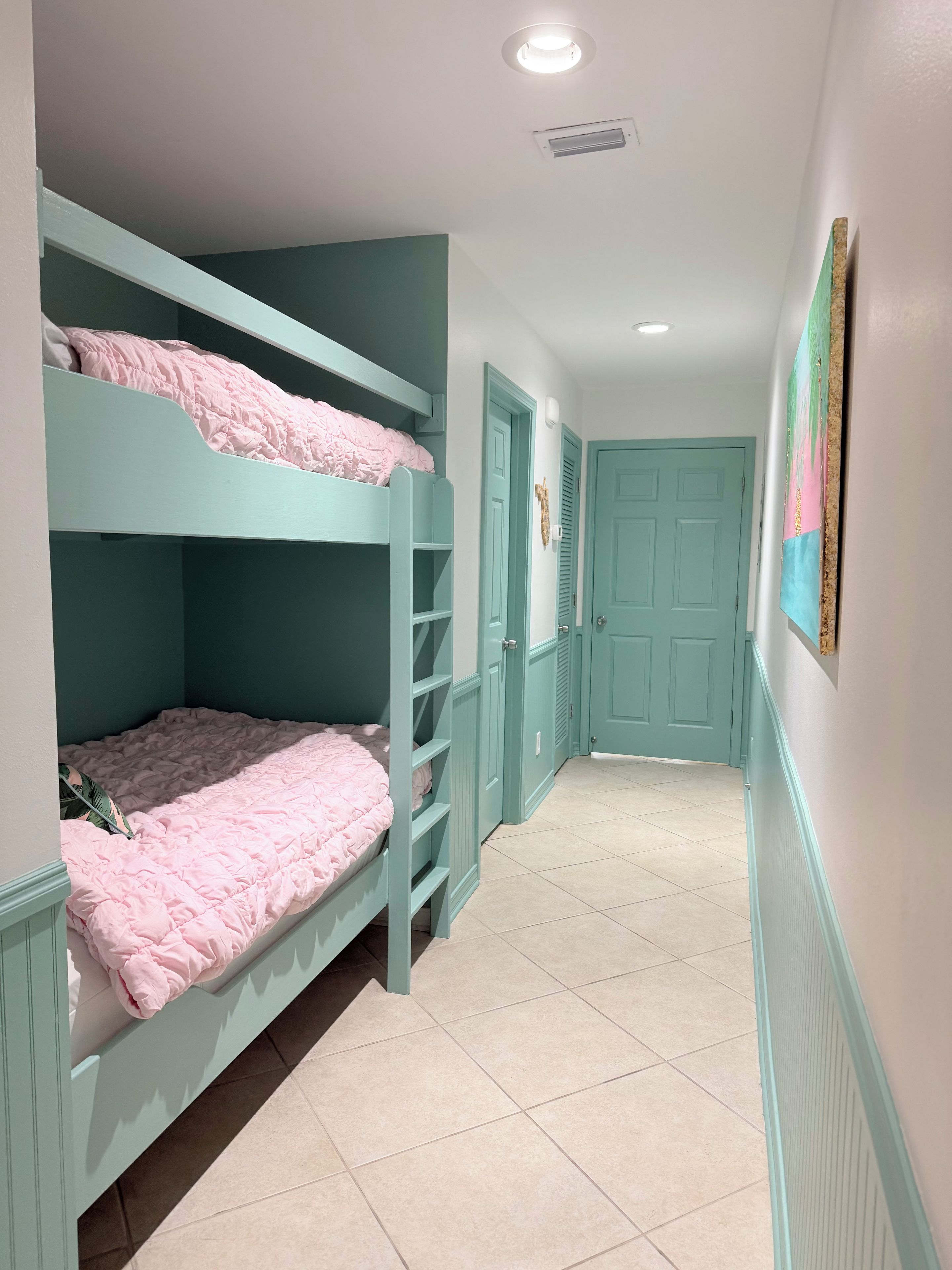 A narrow hallway with bunk beds on one side and a door at the end.