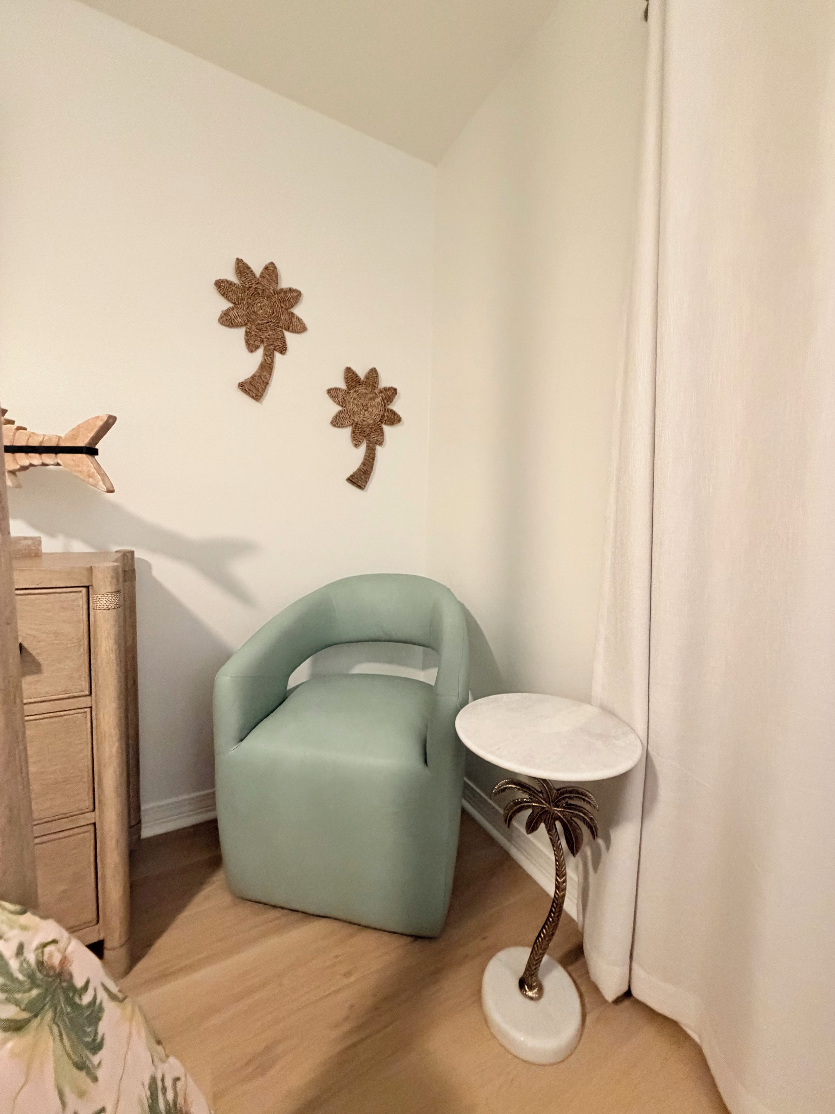 Une pièce comprenant une chaise bleu clair, une petite table ronde avec un plateau blanc et deux éléments décoratifs fixés au mur.