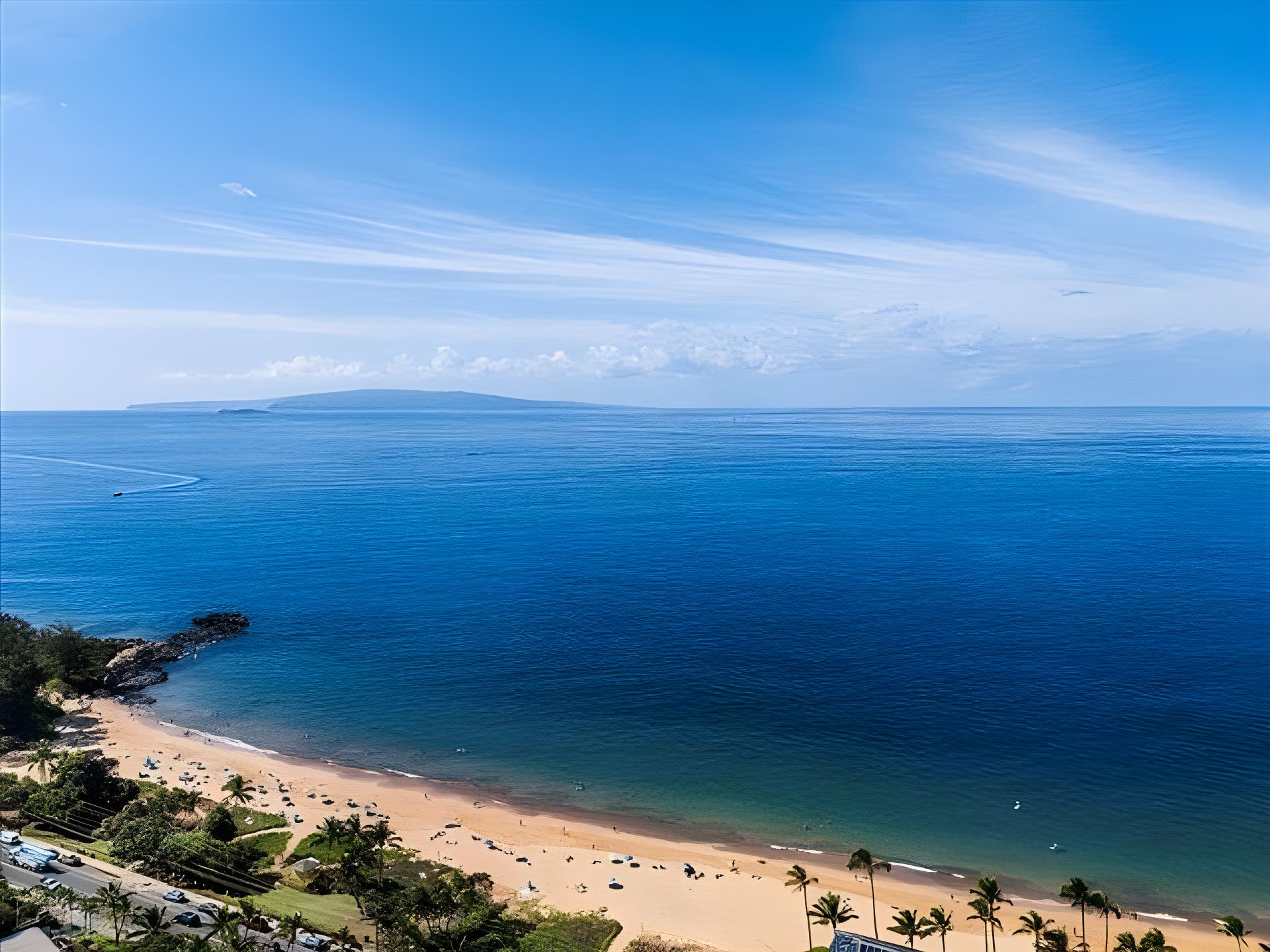 Une plage à l’eau d’un bleu cristallin, avec un rivage sablonneux et des palmiers.