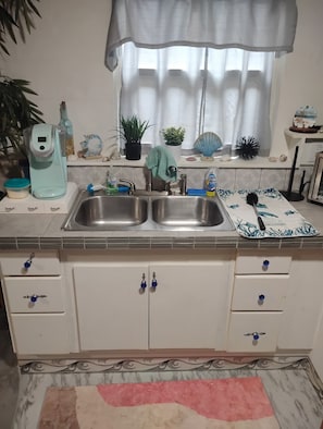 A kitchen with a double sink, a coffee maker, and various decorative items. - Cocoa's Coziest Ice Cold Beach Hut minutes from everything! (Cocoa)