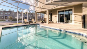A swimming pool with a glass enclosure, outdoor seating, and a view of neighboring buildings. - Orlando Family Paradise with Private Pool & Resort (Four Corners)