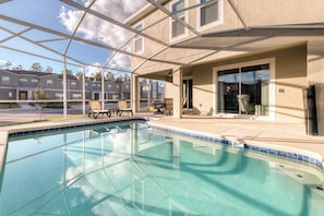 Piscina com cobertura de vidro, área de estar ao ar livre e vista para edifícios próximos.