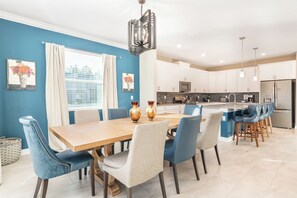 Een moderne keuken met witte kasten, een centraal eiland en blauwe stoelen.