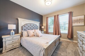 A bedroom with a tufted headboard, a large bed, two bedside tables with lamps, a dresser, and a window with curtains. - Orlando Family Paradise with Private Pool & Resort (Four Corners)