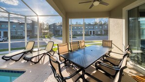 A covered patio with a pool, outdoor seating, and a view of residential buildings. - Orlando Family Paradise with Private Pool & Resort (Four Corners)