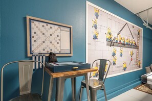 Ein Scrabble-Brettspiel auf einem Tisch mit Scrabble-Fliesen und einer Tüte daneben.