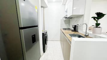 A modern kitchen with a stainless steel refrigerator, a built-in washing machine, a gas stove, and a sink.