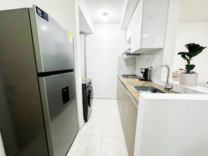Una cucina moderna con frigorifero in acciaio inossidabile, lavatrice integrata, piano cottura a gas e lavello.