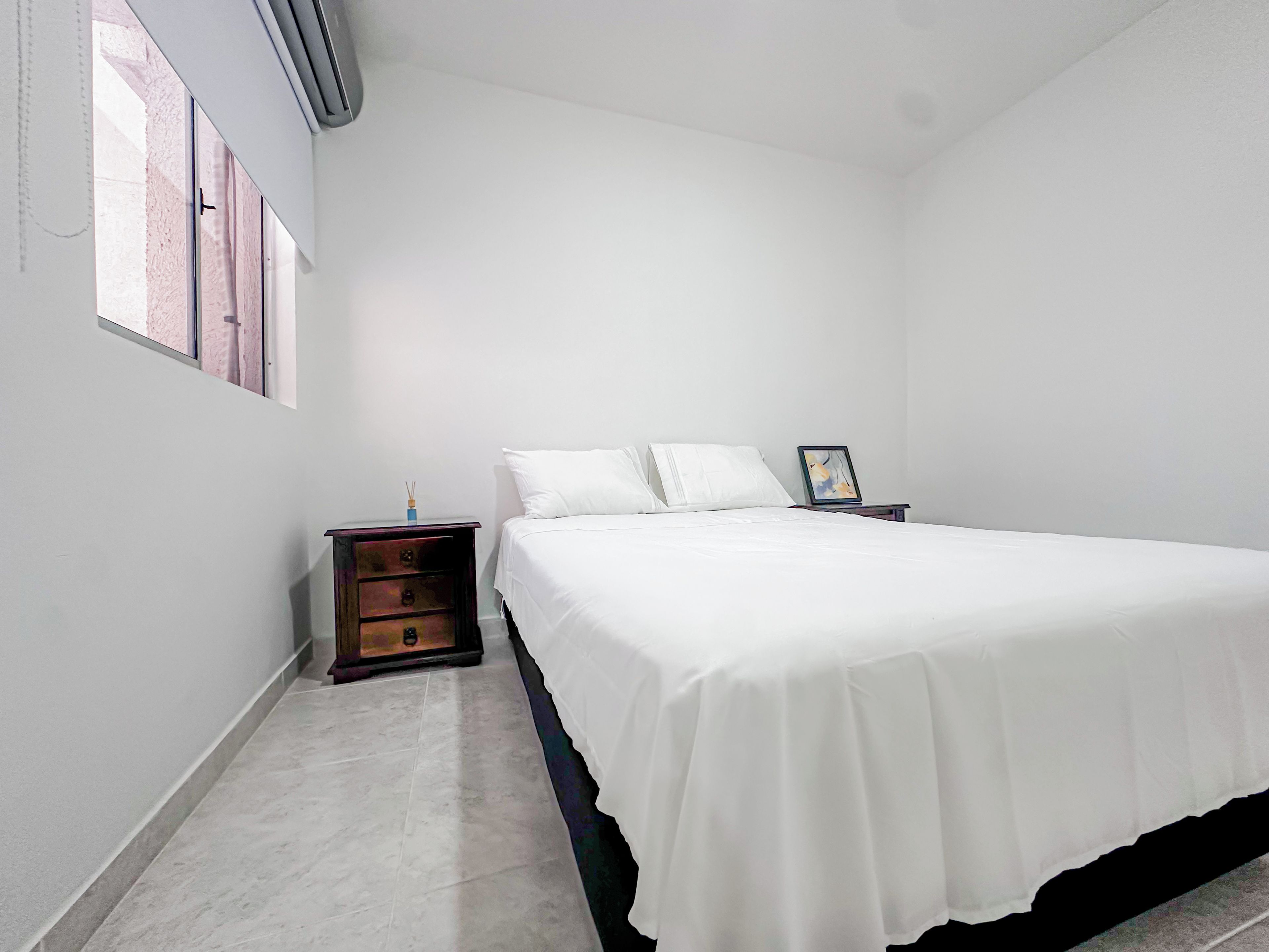 Una camera da letto con un letto, un comodino, un tavolino e una finestra.