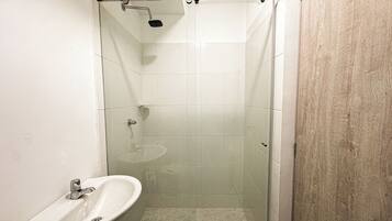 Un bagno piccolo con cabina doccia in vetro, un lavandino e una parete in legno.