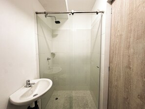 Un bagno piccolo con cabina doccia in vetro, un lavandino e una parete in legno.