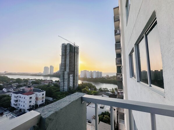A high-rise building with a construction crane, surrounded by other buildings and a river. - Apartamento en Cartagena (Torices)
