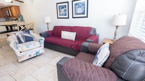 A living room with a sofa, armchair, and a dining table with chairs. There are two framed artworks on the wall. - 2BR Half Block to Beach, Garage, Heated Pool (South Padre Island)