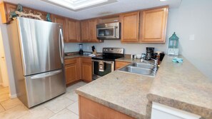 A kitchen with stainless steel appliances, wooden cabinets, a granite countertop, and a built-in oven. - 2BR Half Block to Beach, Garage, Heated Pool (South Padre Island)
