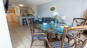 A dining area with a round glass table, blue and white plates, and wicker chairs. - Gulfview - 250 yrds to Beach Bbq Poolside (South Padre Island)