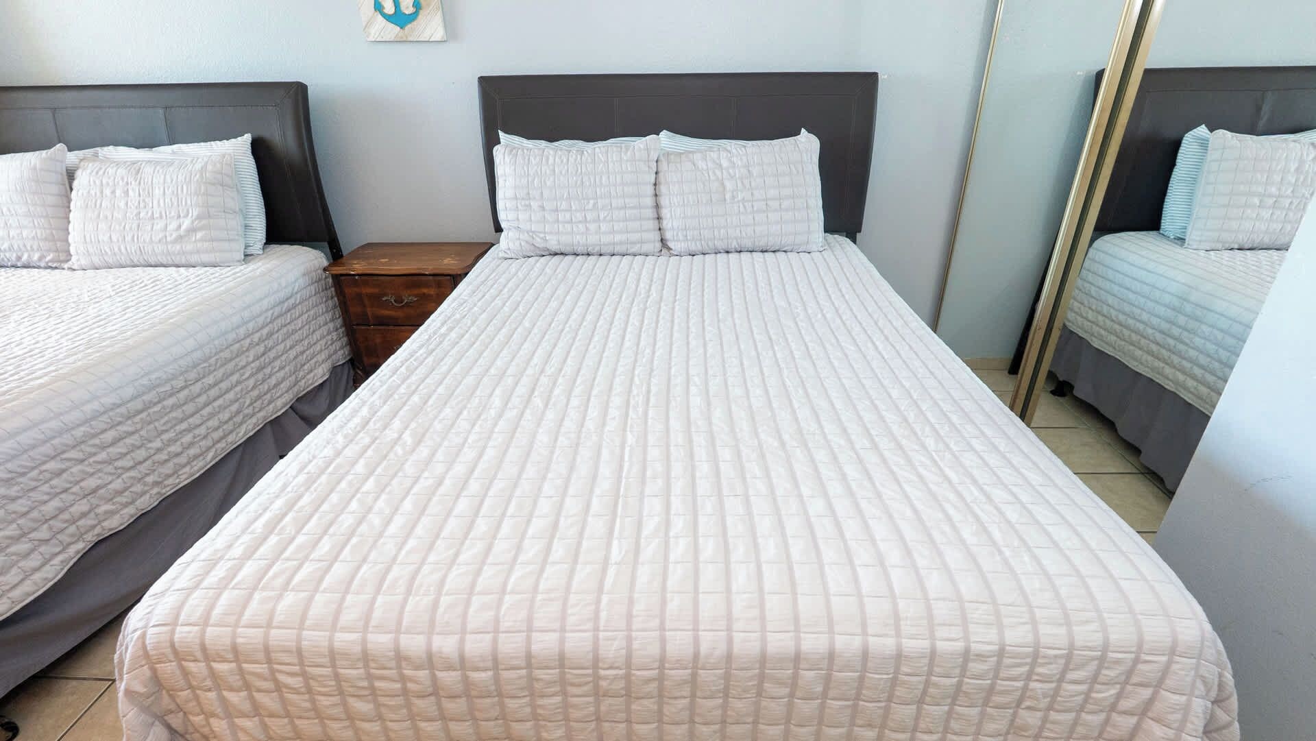 Een hotelkamer met een groot bed, twee nachtkastjes en een spiegel.